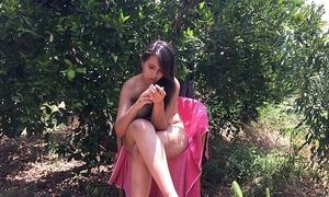 Chica joven de eighteen años sentada desnuda entre árboles